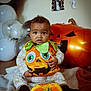 Leo is registered to the contest to win money with this photo: baby, pumpkin_costume, halloween, infant, balloons, blanket, decorations, jack_o_lantern, indoor, cute, child, holiday, orange, green, plush, sitting, floor, costume, festive, portrait