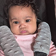 Ophelia joined the competition — help win amazing prizes! baby, child, curly_hair, car_seat, seatbelt, pink_clothing, gray_pads, serious_expression, infant, closeup, indoors, safety_harness, person, cute, young_child, portrait, soft_texture, child_seat, baby_face, strapped_in