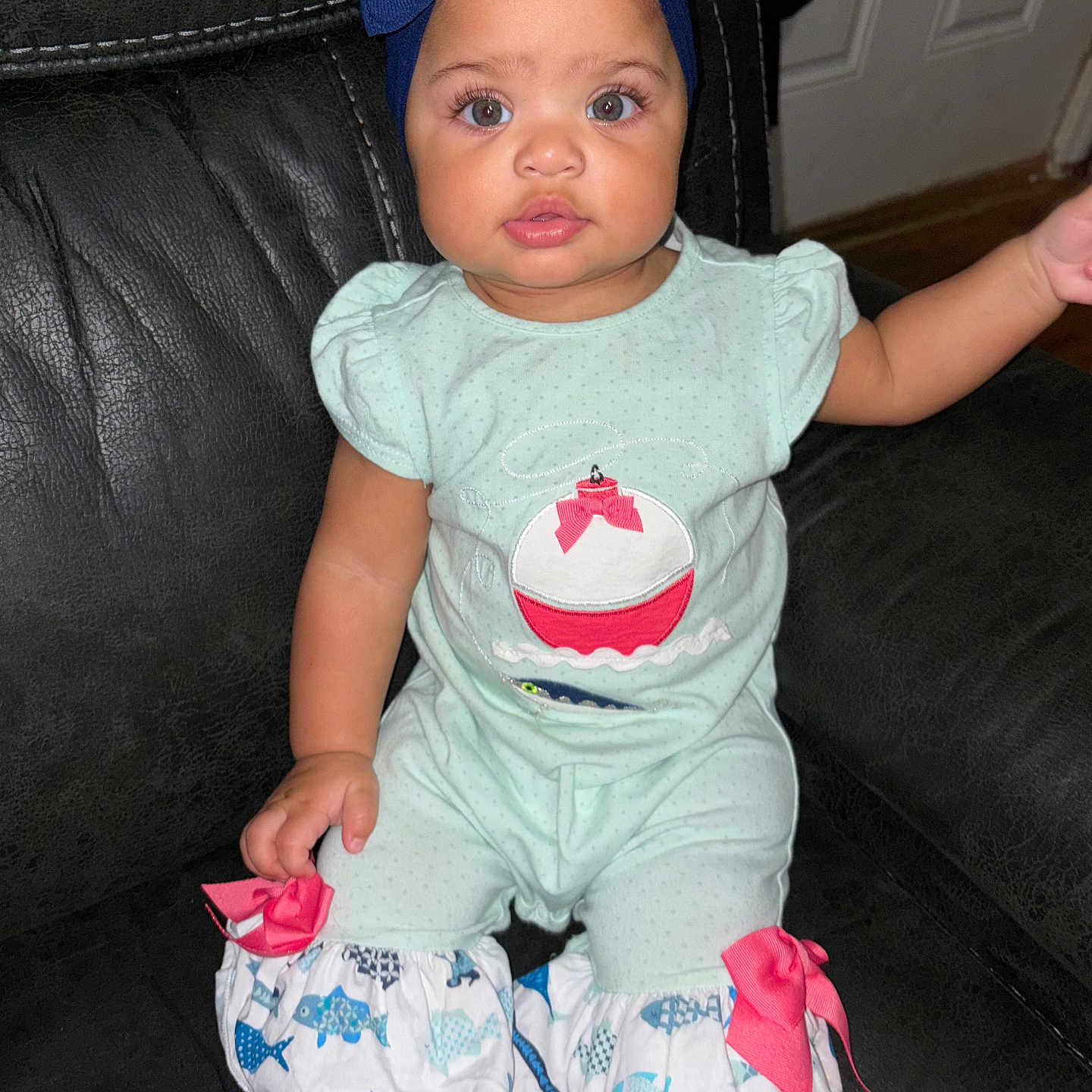 Jazleigh is registered to the contest to win money with this photo: baby, barefoot, black_couch, blue_bow, child, chubby_cheeks, clothing, curious, cute, fish_pattern, girl, headband, indoor, infant, pink_bows, portrait, romper, sitting, toddler, wide_eyes