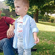 Teo participe au concours pour gagner de l'argent avec cette photo : child, toddler, outdoor, grass, tree, person, adult, shirt, pants, sneakers, sunlight, shadow, nature, park, casual_clothing, greenery, daylight, curious, standing, relaxing