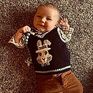 Braxton joined the competition — help win amazing prizes! baby, child, infant, carpet, clothing, sweater_vest, bunny_design, pacifier, smile, happy, cute, lying_down, indoors, toddler, portrait, person, head, hands, brown_pants, plaid_shirt
