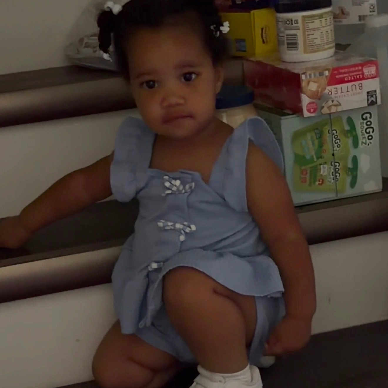 Blessin is registered to the contest to win money with this photo: blue_dress, boxes, casual, child, curious, curly_hair, expression, hair_buns, home, household_items, indoor, person, plastic_bag, portrait, sitting, snack_box, stairs, toddler, white_shoes, young_child