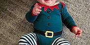 Noélan participe au concours pour gagner de l'argent avec cette photo : baby, infant, child, carpet, floor, costume, elf, striped_pants, red_hat, green_outfit, smiling, happy, hands, feet, indoor, cute, playful, person, apparel, portrait