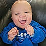 Noélan participe au concours pour gagner de l'argent avec cette photo : baby, child, smiling, happy, blue_sweatshirt, fists, face, skin, sitting, leather_couch, indoor, portrait, cute, joyful, mouth_open, tongue, hands, eyes, infant, casual_clothing