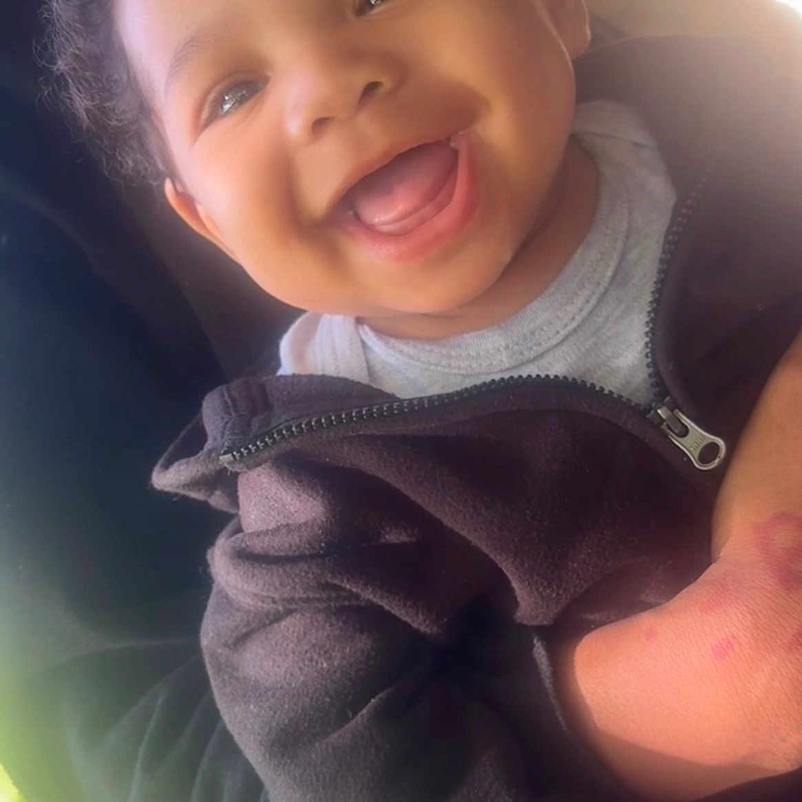 Kaizen is registered to the contest to win money with this photo: toddler, child, smiling, happy, face, curly_hair, jacket, zipper, person, outdoor, natural_light, portrait, closeup, cute, infant, holding, joy, expression, skin, hand