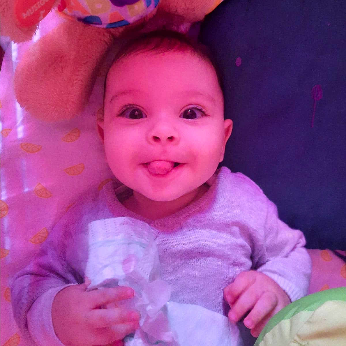 Ahmed participe au concours pour gagner de l'argent avec cette photo : baby, bed, blanket, child, clothing, cute, diaper, expression, face, hand, happy, indoors, infant, lying_down, pillow, playful, smiling, soft_toy, tongue_out, toy