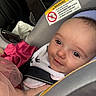 baby, car_interior, car_seat, child, closeup, clothing, cute, fabric, face, head, infant, person, pink, portrait, safety, seat, seatbelt, smile, tulle, warning_label