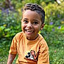 child, boy, smiling, outdoor, garden, greenery, mickey_mouse, tshirt, short_sleeve, happy, cute, portrait, young, casual_clothing, nature, daylight, sitting, curly_hair, playful, bright