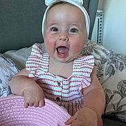 Harper joined the competition — help win amazing prizes! baby, child, headband, bow, smiling, happy, basket, pink, striped_dress, sitting, bed, pillow, floral, indoors, cute, infant, holding, playful, portrait, joyful