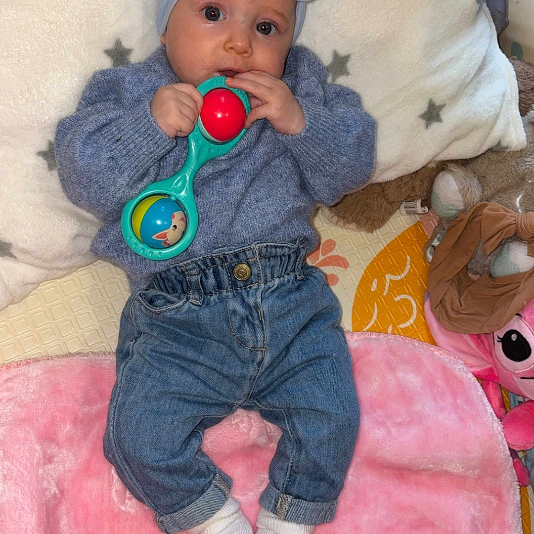 Yeliz a rejoint le concours — aidez-le/la à gagner de superbes lots ! baby, blue_sweater, child, colorful, cozy, cute, headband, indoor, infant, jeans, lying_down, pillow, pink_blanket, playtime, portrait, rattle, soft_texture, star_pattern, toy, white_socks