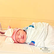 Thalia joined the competition — help win amazing prizes! newborn, baby, sleeping, hospital, blanket, pink_hat, bunny_ears, bassinet, infant, wrapped, cute, peaceful, child, face, headwear, indoors, soft_light, resting, person, healthcare
