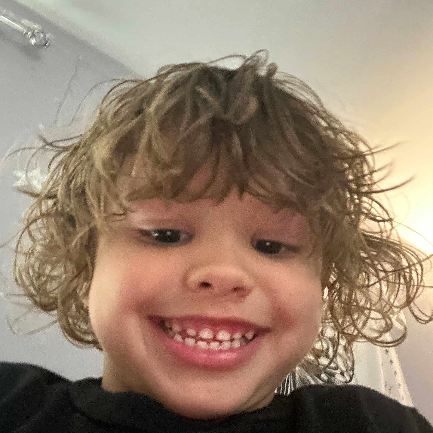 Maddox joined the competition — help win amazing prizes! black_shirt, casual, child, closeup, curly_hair, cute, expression, face, hair, happy, head, indoor, kid, light, person, portrait, smiling, teeth, wall, young