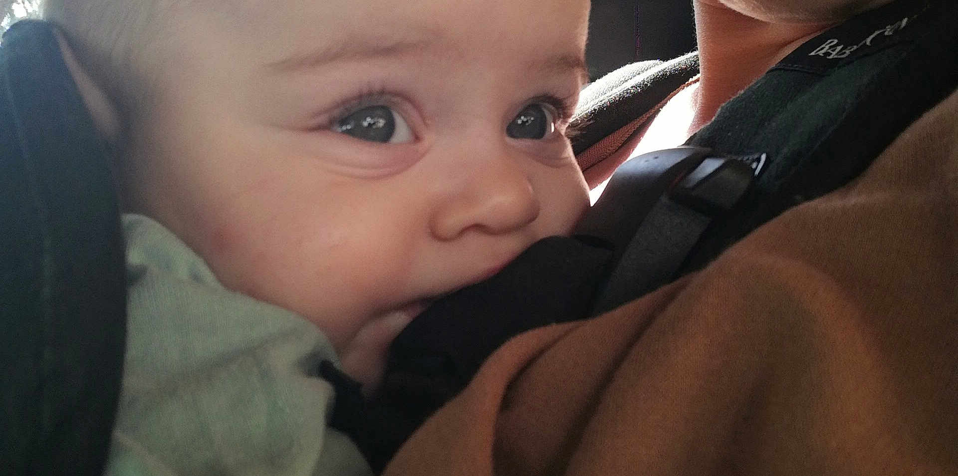 Aïssa a rejoint le concours — aidez-le/la à gagner de superbes lots ! baby, close_up, face, child, infant, carrier, straps, biting, skin, light, person, cute, young, eyes, mouth, comfort, soft_light, clothing, human, portrait