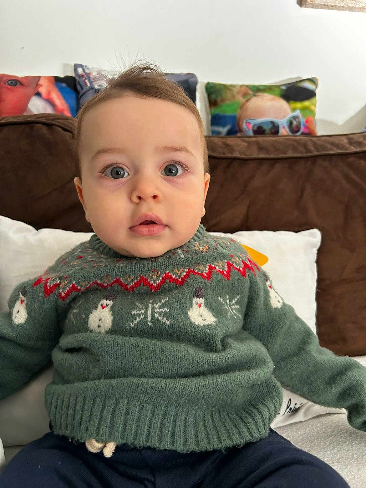Aïssa a rejoint le concours — aidez-le/la à gagner de superbes lots ! baby, child, clothing, couch, curious, cute, eyes, face, green_sweater, home, indoor, infant, person, pillow, portrait, sitting, snowman_pattern, sweater, warm, young_child