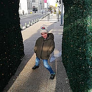 Noah participe au concours pour gagner de l'argent avec cette photo : child, winter_clothing, hat, jacket, street, sidewalk, archway, lights, urban, building, playful, smile, daylight, shadow, concrete, pedestrian, outdoor, casual, fun, young