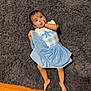 Tripat is registered to the contest to win money with this photo: baby, child, blue_dress, thumb_sucking, lying_down, curious, dark_rug, fluffy_rug, wooden_floor, barefoot, indoor, person, cute, toddlers, infant, home, flooring, footwear, sleepwear, portrait