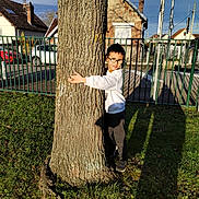 Lyam a rejoint le concours — aidez-le/la à gagner de superbes lots ! child, boy, tree, glasses, hugging, grass, shadow, house, car, fence, outdoor, sunlight, casual_clothing, smiling, side_view, daytime, nature, yard, residential_area, person