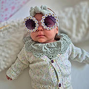 Victoire participe au concours pour gagner de l'argent avec cette photo : baby, infant, sunglasses, flower_frame, headband, knitted_sweater, clothing, portrait, cute, fashion, accessory, indoor, soft_lighting, child, person, small_child, white_background, cozy, closeup, adorable