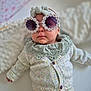 baby, infant, sunglasses, flower_frame, headband, knitted_sweater, clothing, portrait, cute, fashion, accessory, indoor, soft_lighting, child, person, small_child, white_background, cozy, closeup, adorable