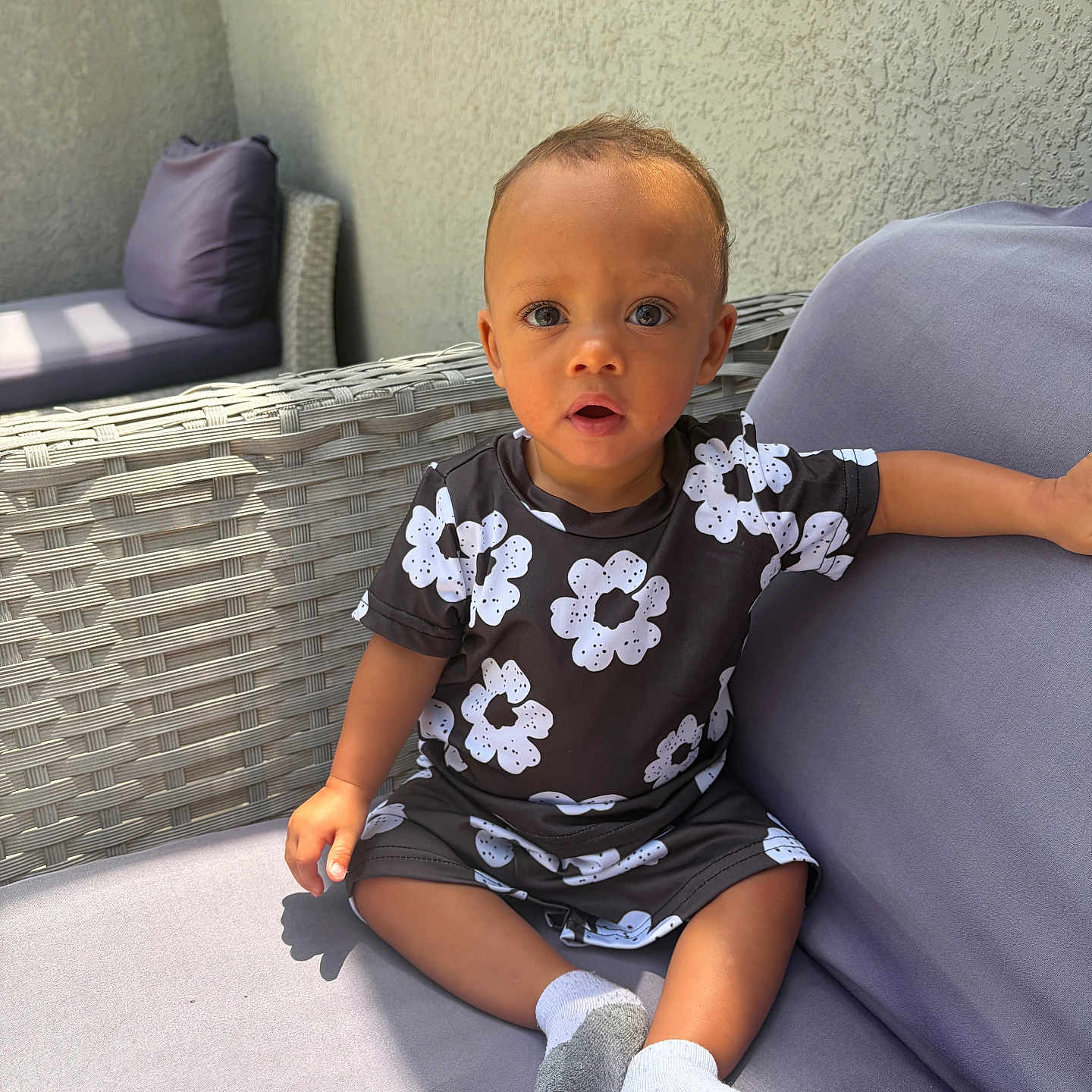 Nico Valmir is registered to the contest to win money with this photo: toddler, child, baby, outdoor, sofa, cushion, wicker, clothing, socks, person, portrait, expression, curious, sunlight, wall, furniture, seat, young_child, casual, relaxed