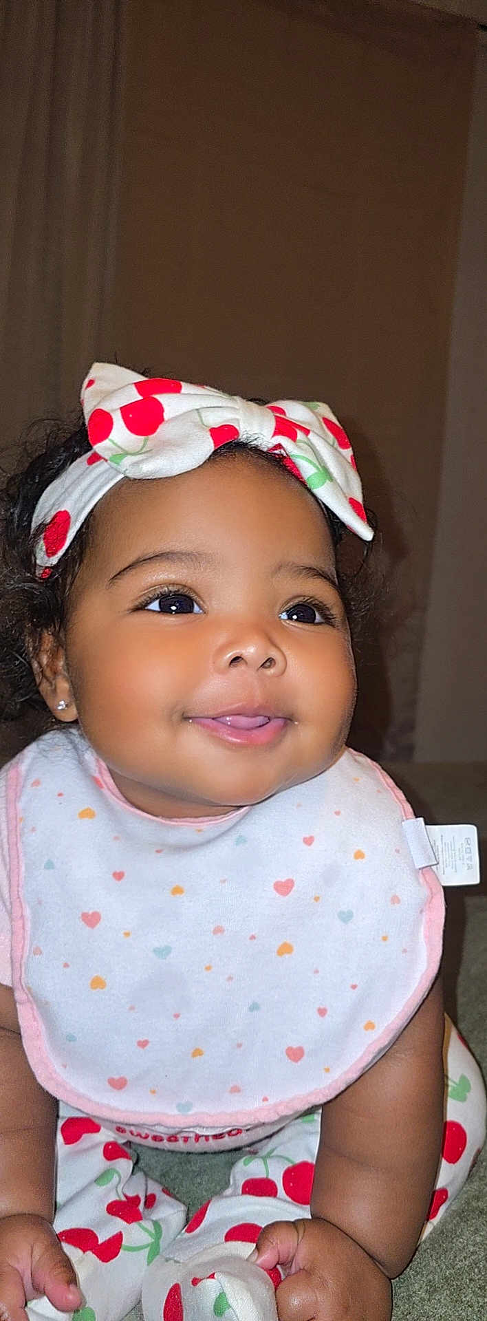 Emery joined the competition — help win amazing prizes! baby, infant, smiling, face, headband, bow, cherry_pattern, bib, clothing, crawling, hands, cute, happy, portrait, child, indoors, skin, person, closeup, young