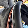 baby, car_seat, infant, blue_clothing, handle, car_interior, window, seat, child, partial_face, fabric, black, brown_trim, transportation, vehicle, safety_seat, infant_clothing, baby_carrier, seat_belt, outdoor_view