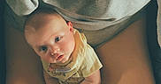 Connor is registered to the contest to win money with this photo: baby, casual_clothing, child, comfort, cozy, curious, face, hands, head, human, indoor, infant, legs, looking_up, person, purple_cloth, relaxed, seated, skin, sweatshirt