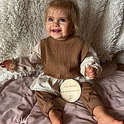 ève participe au concours pour gagner de l'argent avec cette photo : toddler, child, smiling, blue_eyes, hair_bow, brown_clothing, knit_vest, plush_blanket, soft_texture, wooden_plaque, first_birthday, sitting, indoors, happy, cute, portrait, baby, floor, cozy, celebration