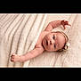 adorable, arm, baby, blanket, child, closeup, comfort, cute, expression, flower, headband, indoors, infant, lying_down, newborn, peaceful, portrait, skin, soft_texture, toddler