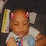 Braylin is registered to the contest to win money with this photo: toddler, child, baby, car_seat, bottle, mickey_mouse, milk, drinking, white_shirt, face, hand, sitting, indoors, cute, red_horns, doodle, infant, young_child, peaceful, portrait