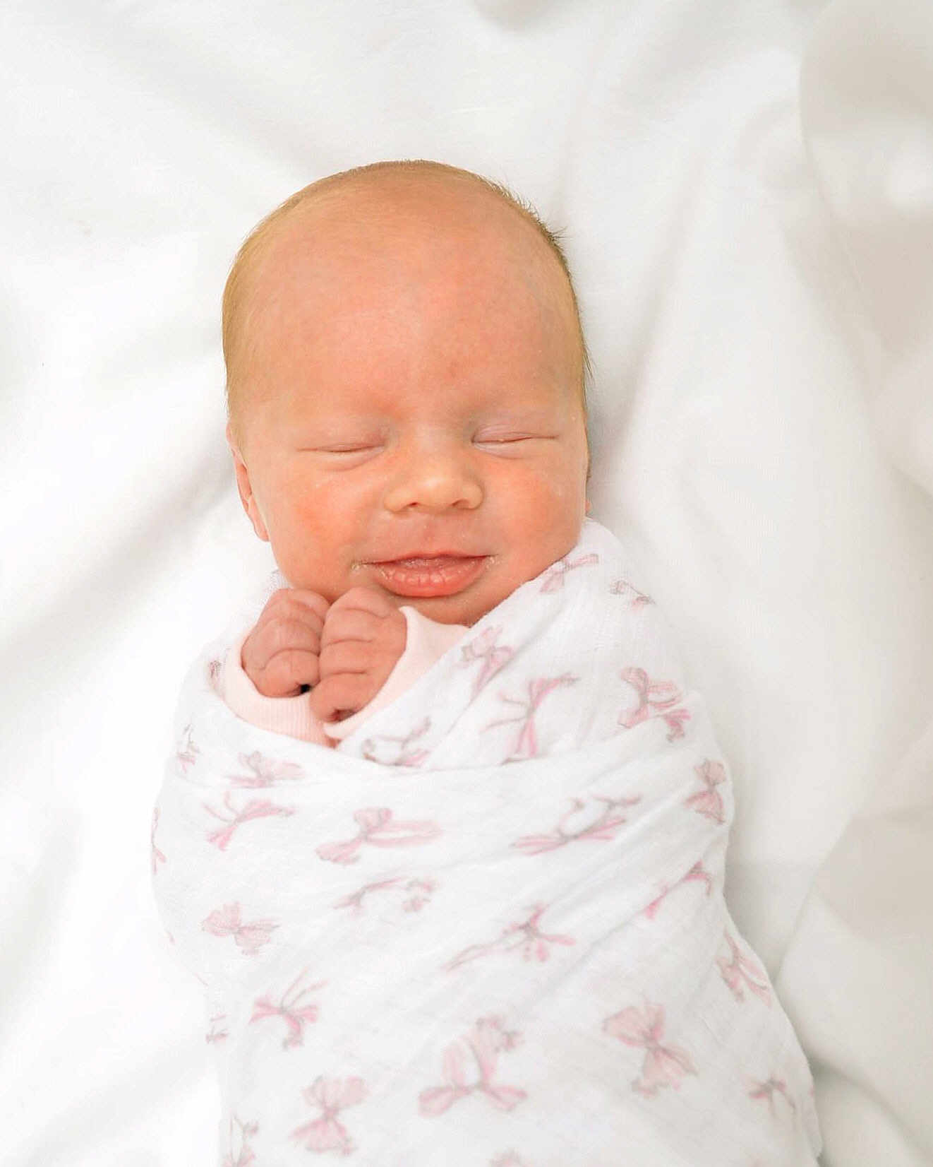 Emberlynn is registered to the contest to win money with this photo: newborn, baby, swaddled, blanket, pink_bows, sleeping, smiling, infant, cute, peaceful, soft, closeup, wrapped, hands, face, portrait, white_background, cozy, resting, toddler