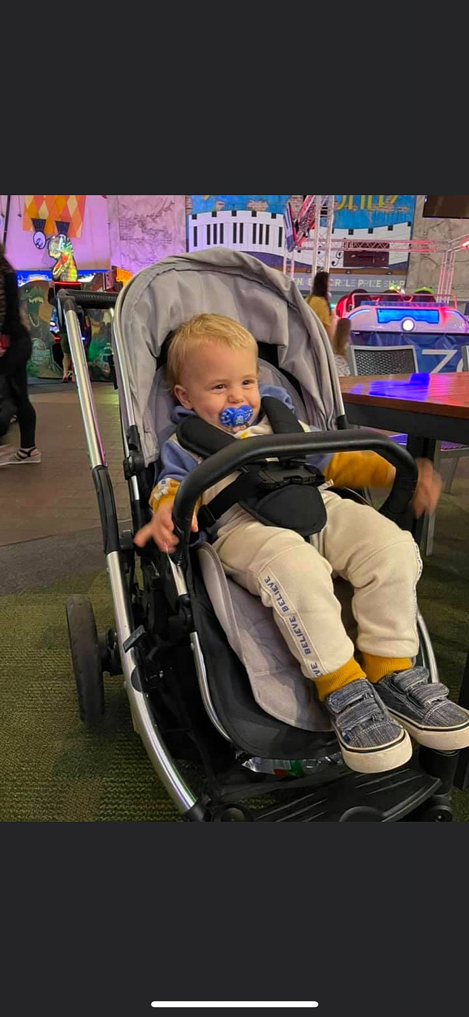 Kylo is registered to the contest to win money with this photo: baby, baby_carriage, baby_products, baby_safety, chair, child, comfort, fun, human_leg, lap, leg, leisure, person, product, shoe, sitting, smile, sneakers, tire, toddler