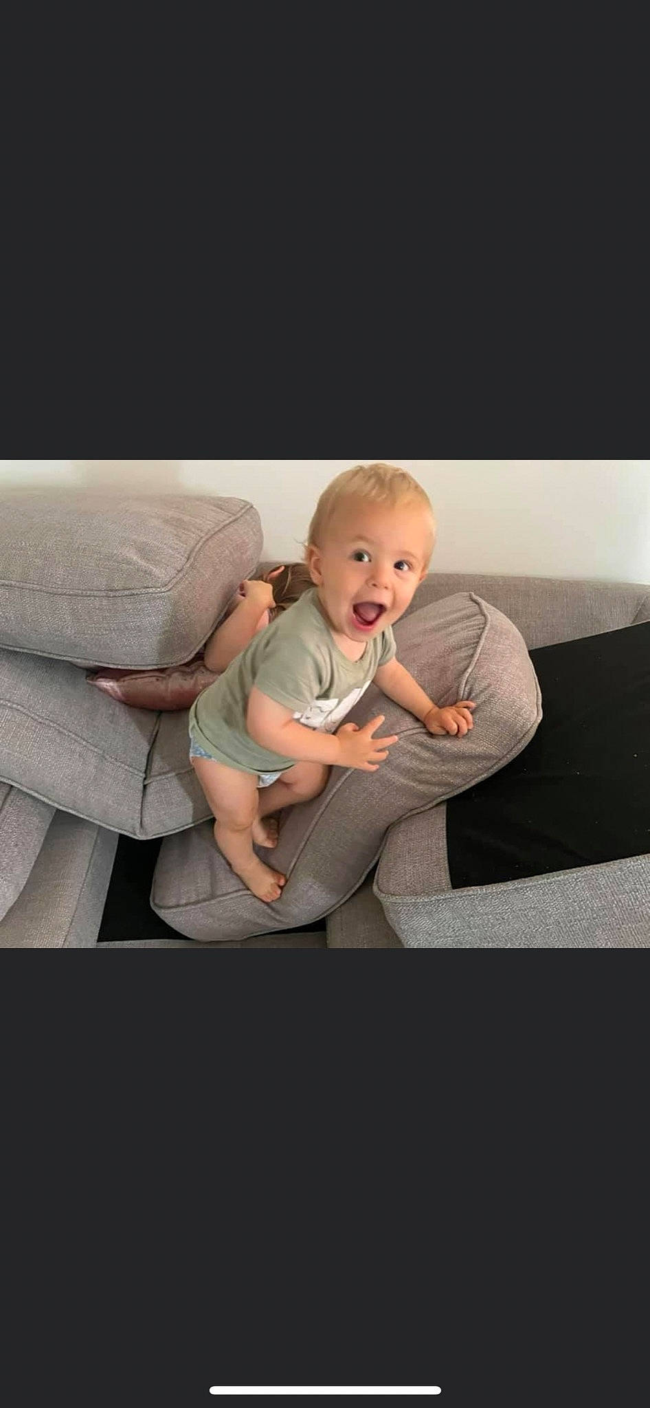 Kylo is registered to the contest to win money with this photo: baby, baby_toddler_clothing, child, comfort, couch, flash_photography, flooring, grey, happy, human_leg, knee, linens, person, room, sitting, sleeve, smile, surprise, t_shirt, thigh