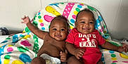 Lujuan Oshea is registered to the contest to win money with this photo: baby, infant, smile, diaper, onesie, red_clothing, colorful_blanket, patterned_blanket, happy, cute, two_babies, sitting, indoors, wall, skin, chubby_cheeks, child, portrait, family, toddler