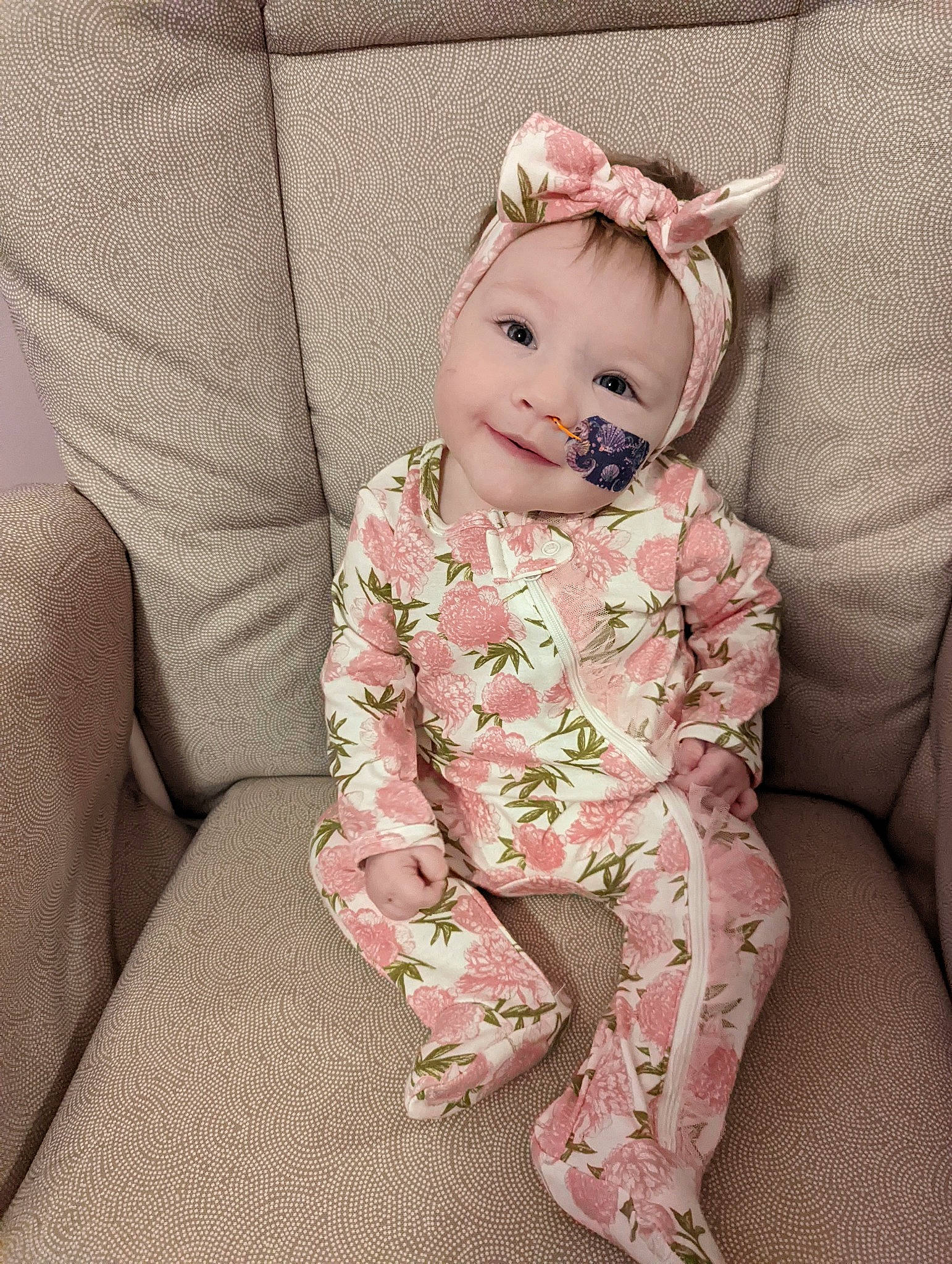 Fiona is registered to the contest to win money with this photo: baby, baby_products, baby_toddler_clothing, cheek, collar, comfort, dress, embellishment, eye, fashion_accessory, headband, headwear, iris, linens, pattern, person, pink, sitting, sleeve, smile
