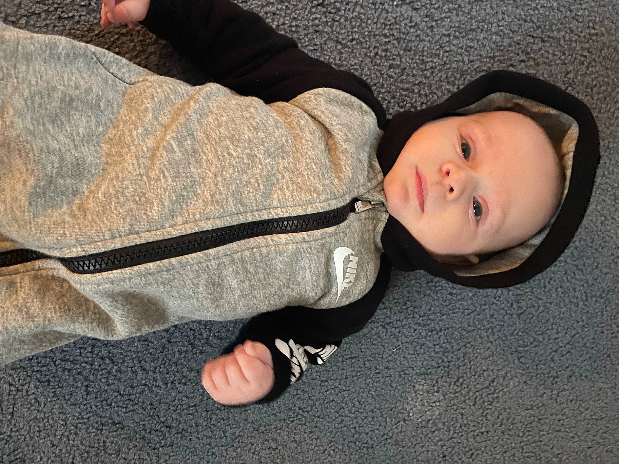 Deacon is registered to the contest to win money with this photo: baby, baby_toddler_clothing, child, comfort, denim, elbow, flooring, foot, gesture, grass, grey, headwear, human_leg, knee, linens, person, sitting, sleeve, toddler, tree