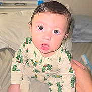 Matthew joined the competition — help win amazing prizes! baby, child, pajamas, cactus_pattern, bed, hand, indoor, person, face, eyes, expression, sleepwear, curious, infant, cute, skin, hair, mouth, sitting, support