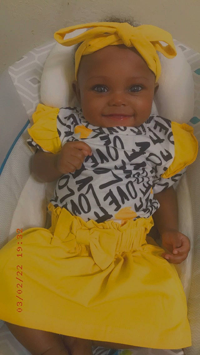 Camiyah is registered to the contest to win money with this photo: baby, baby_toddler_clothing, child, comfort, face, facial_expression, fun, happy, head, headwear, joy, orange, organ, person, product, shorts, skin, sleeve, smile, t_shirt