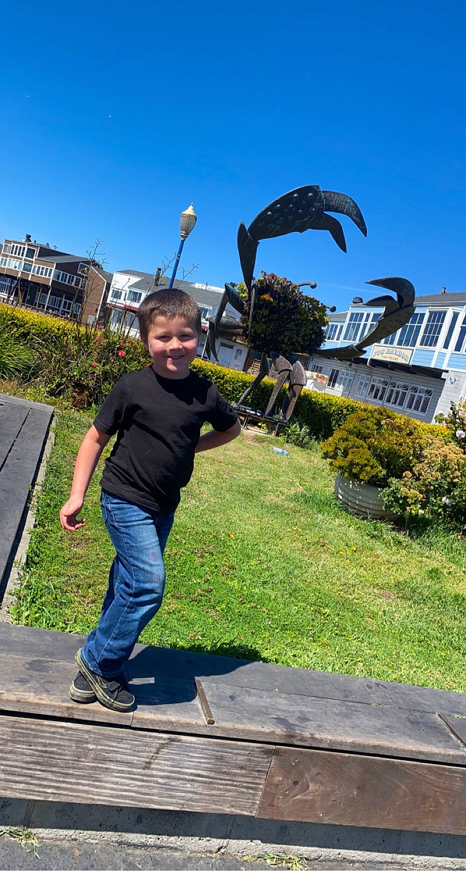 John is registered to the contest to win money with this photo: building, city, fun, garden, grass, happy, jeans, joy, landscape, leaf, leg, leisure, people_in_nature, person, plant, recreation, roof, sky, travel, tree