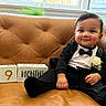 baby, infant, tuxedo, bow_tie, flower, boutonniere, couch, leather, blocks, 9_months, smile, sitting, indoors, window, plant, cute, child, portrait, formal, celebration