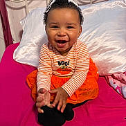 Larissa-Rose is registered to the contest to win money with this photo: baby, child, smiling, happy, orange_clothing, striped_shirt, tutu, bed, pink_bedspread, pillow, indoor, curly_hair, headband, hands, playful, cute, person, home, decor, infant