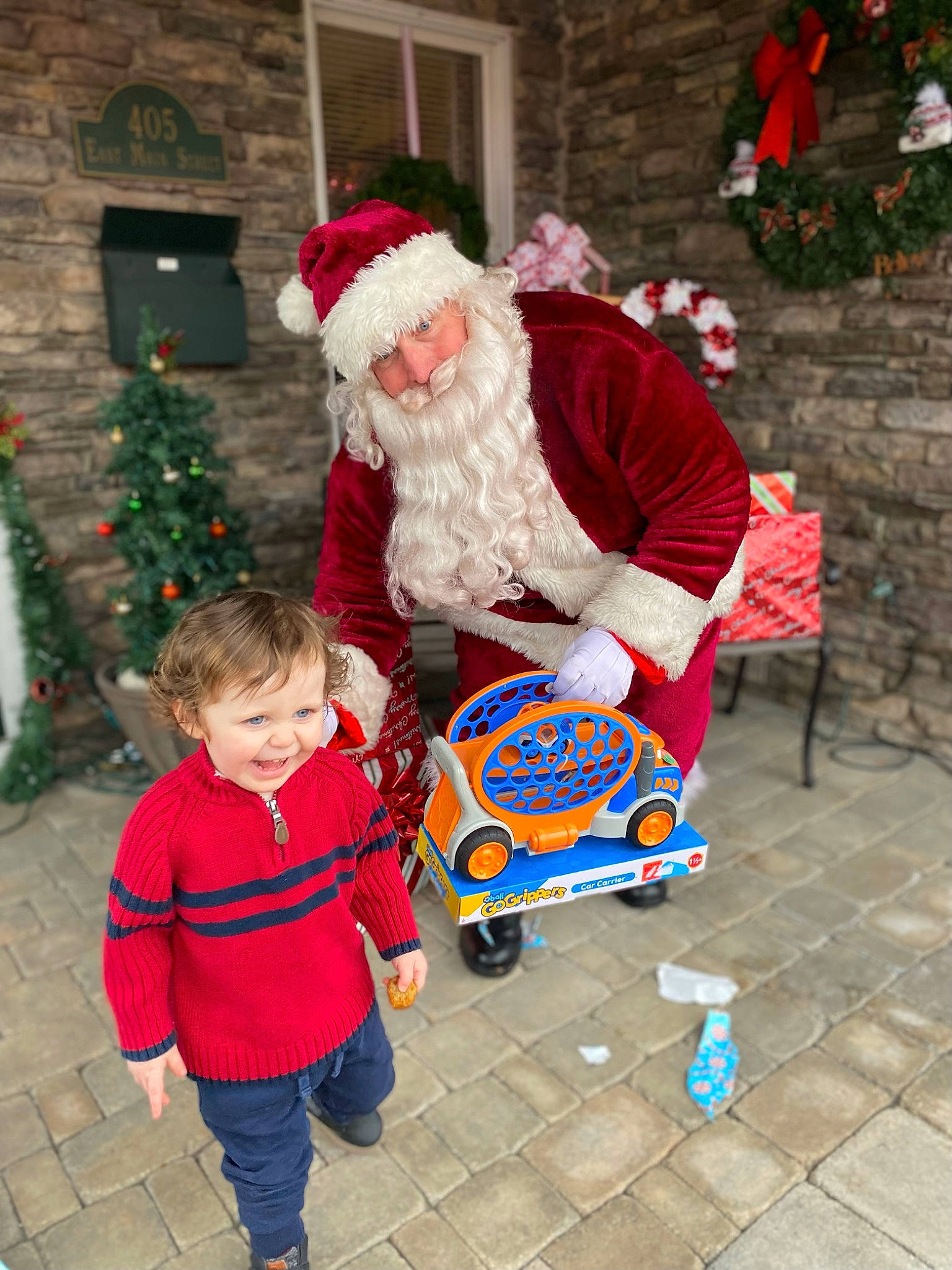 Nolan is registered to the contest to win money with this photo: beard, christmas_decoration, christmas_tree, event, fun, green, happy, hat, headwear, holiday, jacket, joy, lap, leisure, person, red, santa_claus, smile, toddler, tree