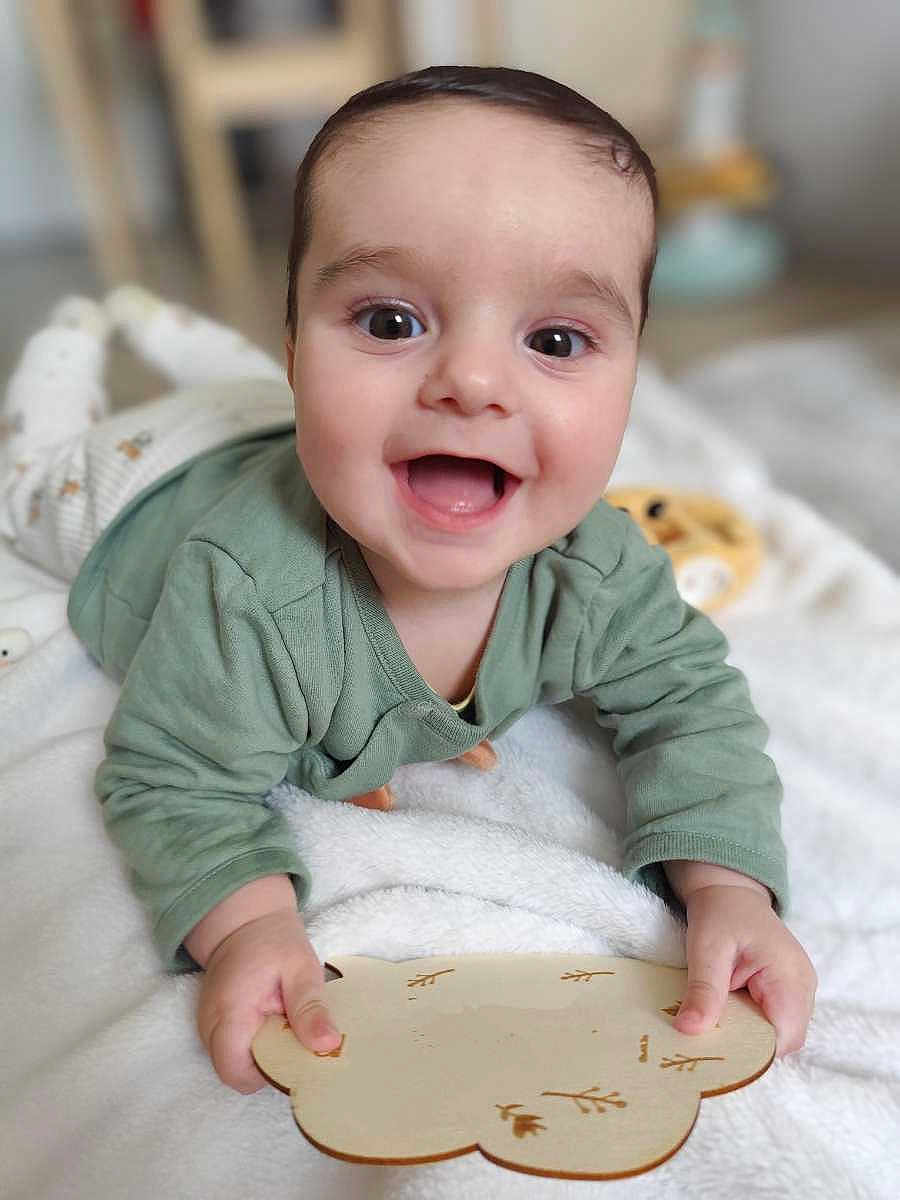 Aaron participe au concours pour gagner de l'argent avec cette photo : baby, infant, smile, smiling, tummy_time, green_shirt, blanket, toy, wooden_toy, hand, face, big_eyes, cute, lying_down, indoors, portrait, soft_texture, play, nursery, blurred_background