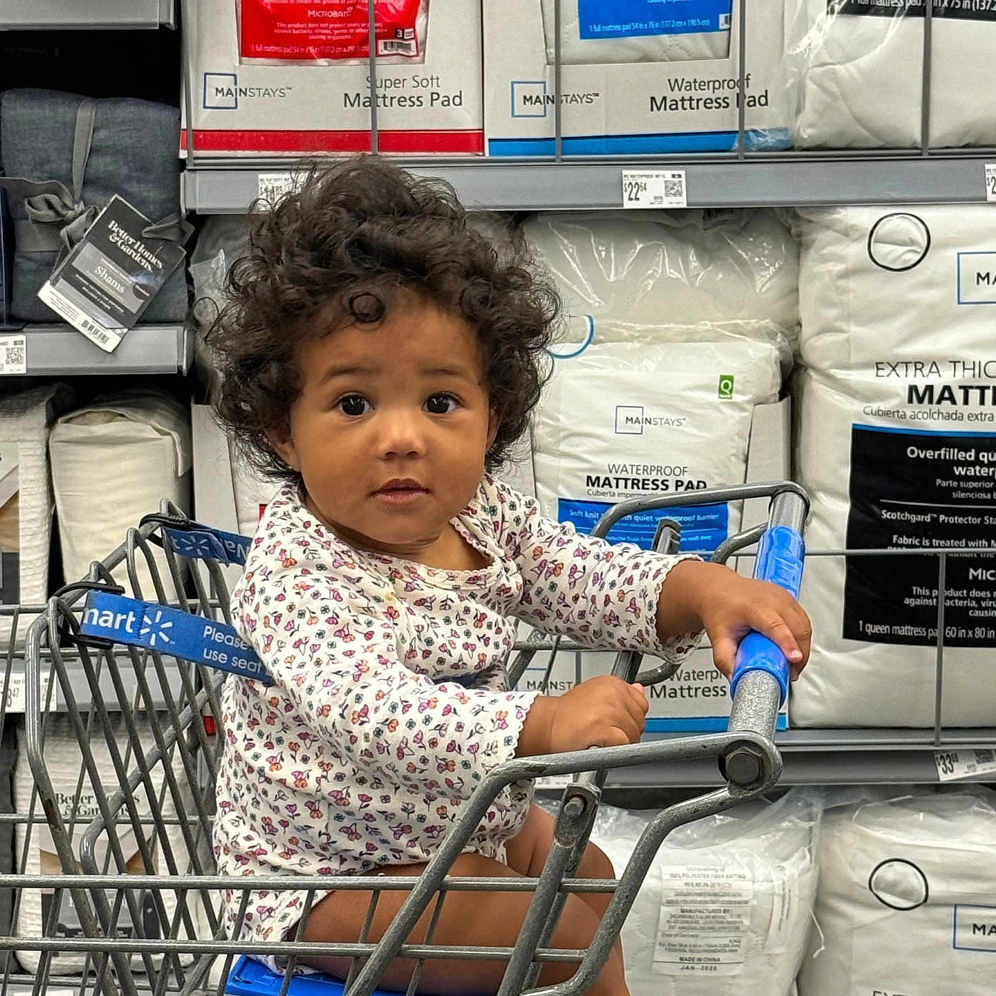 Jamillah is registered to the contest to win money with this photo: aisle, baby, barefoot, child, clothing, curious, curly_hair, indoor, infant, mattress_pad, packaging, product_display, retail, retail_store, seat, shopping, shopping_cart, store, toddler, young_child