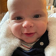 Gaël participe au concours pour gagner de l'argent avec cette photo : baby, infant, close_up, smile, cheeks, eyes, face, fuzzy_coat, jacket, button, skin, portrait, indoors, cuddly, hood, newborn, gaze, happy, cute, soft_texture