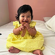 Brielle joined the competition — help win amazing prizes! baby, child, yellow_dress, comb, bed, smiling, happy, indoor, portrait, cute, infant, person, sitting, furniture, pink_wall, soft_lighting, hands, feet, hair, playful