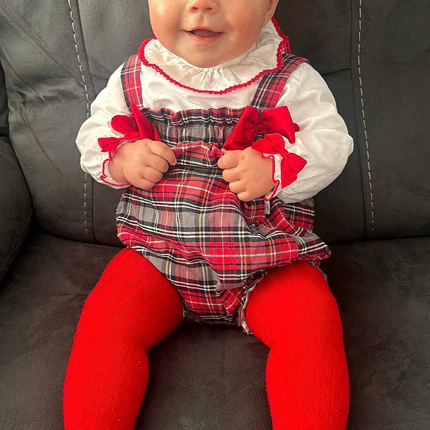 Dolly joined the competition — help win amazing prizes! baby, bright_eyes, child, clothing, couch, cute, face, feet, furniture, hands, happy, indoor, infant, person, plaid_dress, portrait, red_tights, sitting, smiling, white_blouse