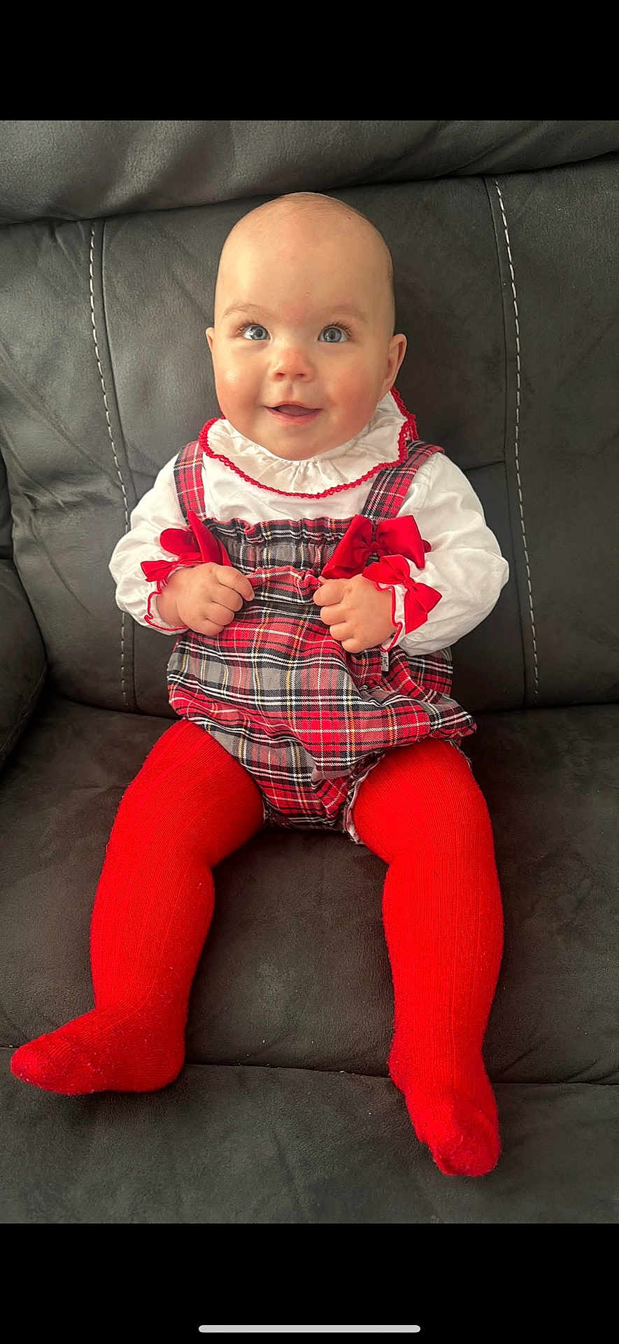 Dolly joined the competition — help win amazing prizes! baby, child, smiling, red_tights, plaid_dress, white_blouse, couch, indoor, sitting, happy, face, person, cute, portrait, hands, feet, infant, clothing, furniture, bright_eyes