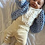 baby, infant, child, bed, blanket, clothing, knitted_cardigan, socks, white, beige, blue, smile, face, hand, thumbs_up, lying_down, cozy, cute, playful, indoors