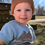 Silas is registered to the contest to win money with this photo: toddler, child, smile, beanie, hat, tshirt, mustang, car_graphic, bench, outdoor, sunlight, portrait, happy, young_child, casual_clothing, daylight, nature, grass, wood, closeup